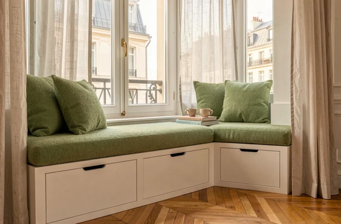 Banquette maçonnée sous fenêtre en boucle vert sauge avec rangements intégrés dans un appartement haussmannien